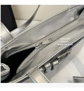 Detailed close-up of smooth silver zipper and metallic fabric on a modern handbag
