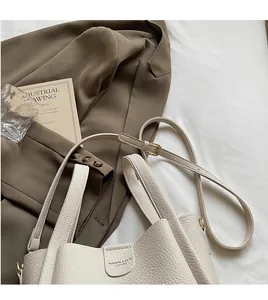 Détail du sac seau crème montrant la texture cuir grainé et la boucle en métal doré