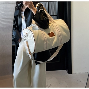 Detail of cream canvas duffel bag with brown leather trim and striped handles