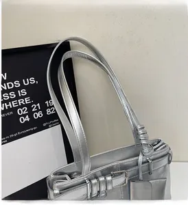 Detail of silver metallic tote bag with sleek double handles and decorative rivets