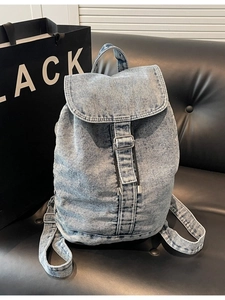 Sac à dos en denim bleu clair avec fermeture à rabat posé sur un canapé en cuir
