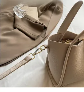 Détail du sac seau en cuir grainé avec ferrures dorées brillantes et bandoulière chic