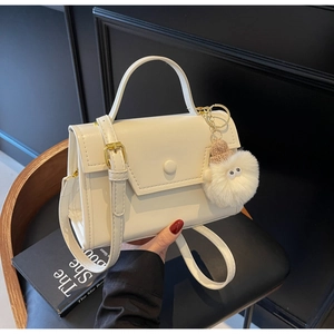 Dettaglio di una borsa in pelle bianco crema con hardware dorato e charm a occhio