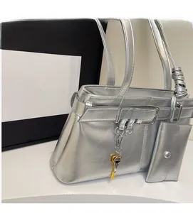 Detail of silver metallic shoulder bag with matching mini pouch and decorative key charm