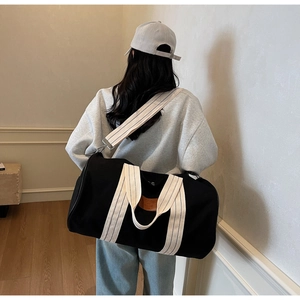 Black canvas travel bag with striped straps shown in a real-life crossbody use case