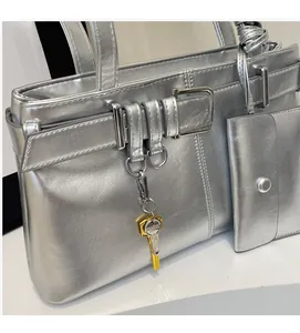 Detail shot of silver metallic shoulder bag with decorative belts and mini pouch accessory