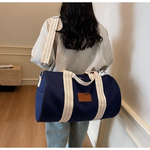 Deep blue canvas travel bag shown on shoulder in a cozy home interior scene