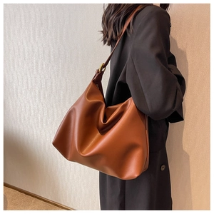 Detail of a large caramel hobo bag showing supple leather texture and gold buckle detail