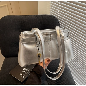 Detail of silver metallic tote bag with gold key pendant and decorative buckle strap