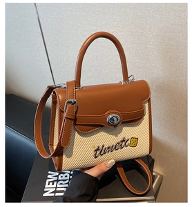 Detail of caramel leather stitching with woven fabric and metal twist lock on handbag