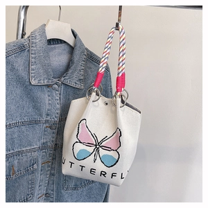 Detail van gebreide emmer tas met pixel vlinderprint en kleurrijke gevlochten handvatten