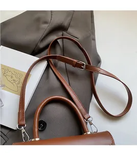 Detailed view of brown leather handbag with adjustable strap and silver buckle hardware