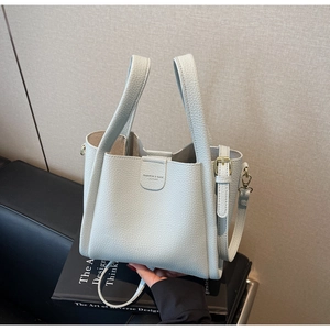Vue détaillée de la texture du cuir lychee et du logo sur le sac seau bleu clair