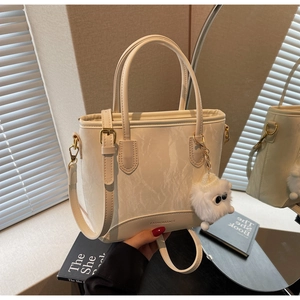 Détails du sac seau crème à motif marbré avec logo et breloque en peluche douce