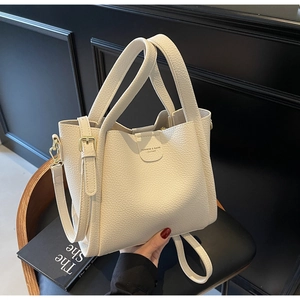 Détail du sac seau beige montrant la texture cuir grainé et la boucle métallique