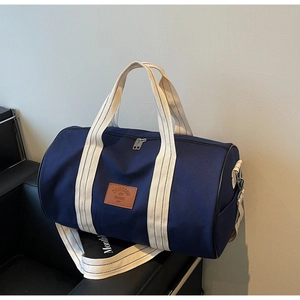 Detail of blue canvas duffel bag with brown faux leather logo and striped handles