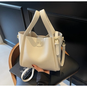 Détail d'un sac seau en cuir grainé ivoire avec finitions dorées et logo raffiné