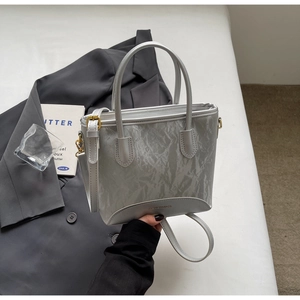 Détail du sac cabas argenté métallisé avec texture froissée sur un blazer gris