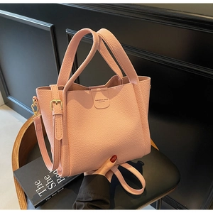 Détail d'un sac seau rose en cuir grainé avec ferrures dorées et gaufrage de mode
