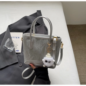 Détail du sac seau plissé argenté avec breloque en peluche et boucles dorées