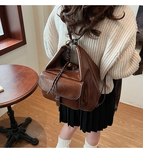 Détail d'un sac à dos en cuir marron avec fermeture à cordon et surpiqûres blanches
