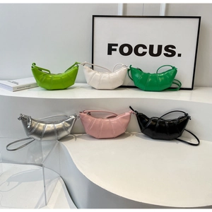 Multiple colorful croissant bags in high-gloss faux leather on stepped display