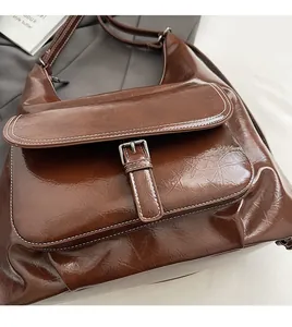 Détail d'un sac en similicuir marron avec texture cirée et coutures blanches