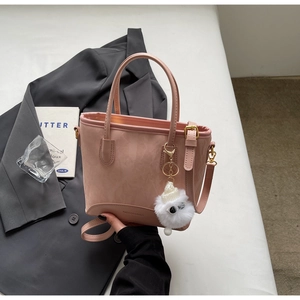 Sac seau rose mat avec charm en peluche et logo élégant sur le fond du sac à main