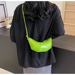 Close-up of bright green croissant bag with smooth faux leather finish and curved shape