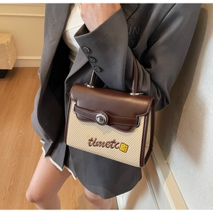 Close-up of woven beige handbag with brown leather trim and metal rotary lock detail