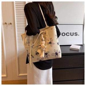 Détail du sac cabas en toile beige avec imprimé floral et breloque lapin en peluche