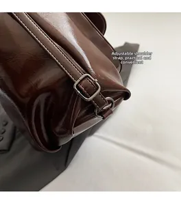 Détail de la bandoulière réglable avec boucle en métal sur le sac à dos marron foncé