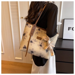 Détail du sac cabas en toile avec imprimé fleuri, anses en cuir et breloque lapin