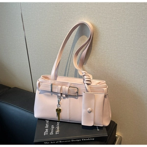 Close-up of light pink leather shoulder bag with buckle detail and key charm accessory