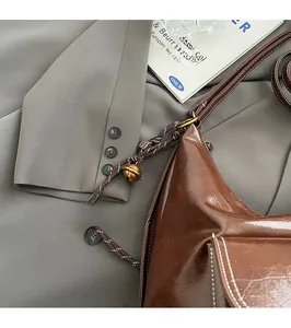 Détail du sac à main rétro en cuir marron avec surpiqûres et breloque en corde tissée