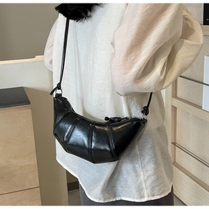 Side view of black croissant bag with quilted faux leather and thin crossbody strap