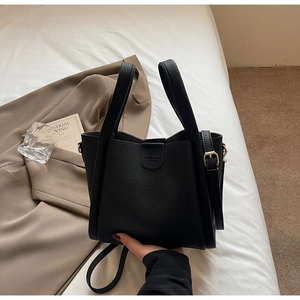 Vue détaillée du sac seau en cuir noir avec ferrures dorées et bandoulière amovible