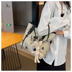 Détail du sac cabas en toile à fleurs avec anses en cuir noir et breloque lapin