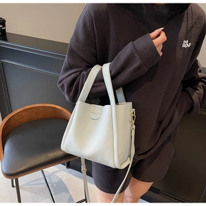 Détail du sac seau bleu clair en cuir grainé avec poignée supérieure et bandoulière