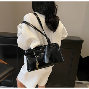 Detail of black glossy leather shoulder bag with silver buckles and a mini pouch attached