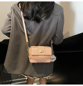 Detailansicht der rosa geflochtenen Mini-Umhängetasche mit Plüsch-Anhänger und Golddekor