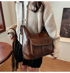 Détail d'un grand sac bandoulière vintage marron foncé en cuir poli sur un mannequin