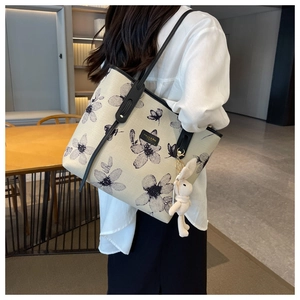 Détail du sac cabas en toile avec imprimé floral noir, anses en cuir et breloque lapin