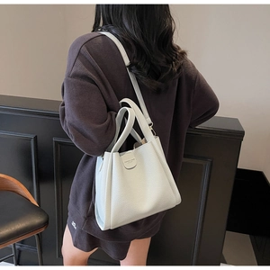 Vue détaillée du sac seau en cuir gris clair à grain de litchi avec anses renforcées