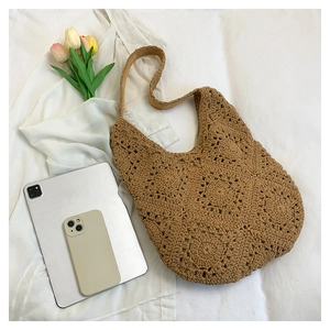 Flat lay of khaki handmade crochet tote bag featuring intricate floral patterns on bed