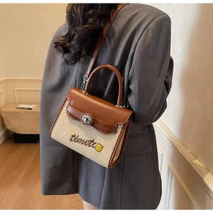 Detailed shot of textured beige woven handbag with brown leather trim and metal clasp
