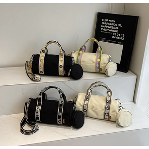Détail de sacs Boston cylindriques noir et beige avec des sangles en toile
