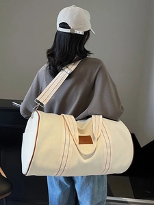 Large beige canvas travel duffel bag with brown leather trim and adjustable shoulder strap