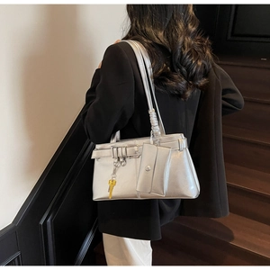 Metallic silver leather tote bag detail with buckles and y2k charms on a model
