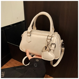 Detail of cream bowling bag with glossy finish and heart charm on the side